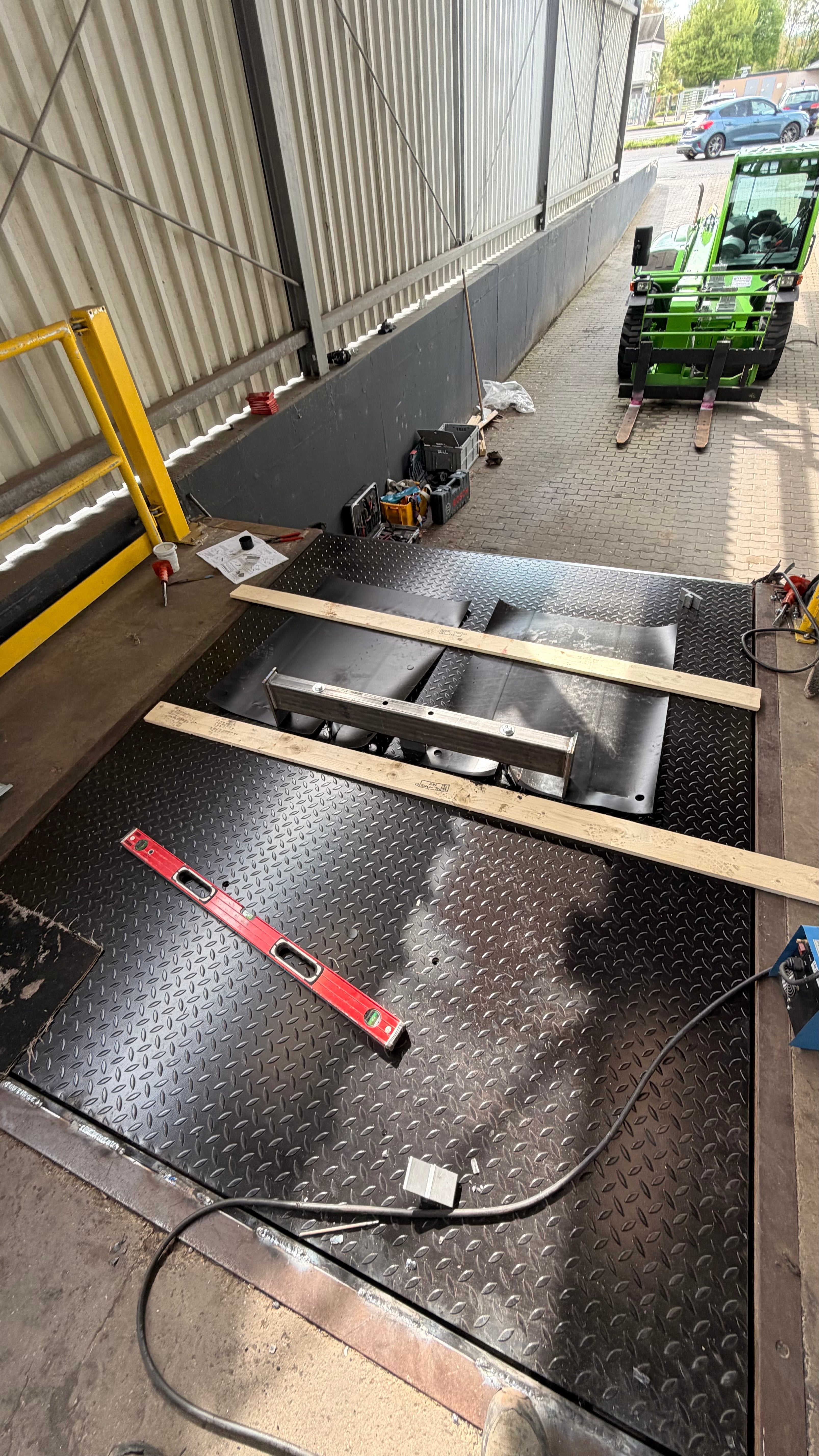 Defekte Überladebrücke an einer Laderampe mit Rampensteuerung, Hydraulikaggregat, Hydraulikzylinder, Anfahrpuffer und Ampeltechnik als Verladetechnik-Ersatzteile von Tormeister24.