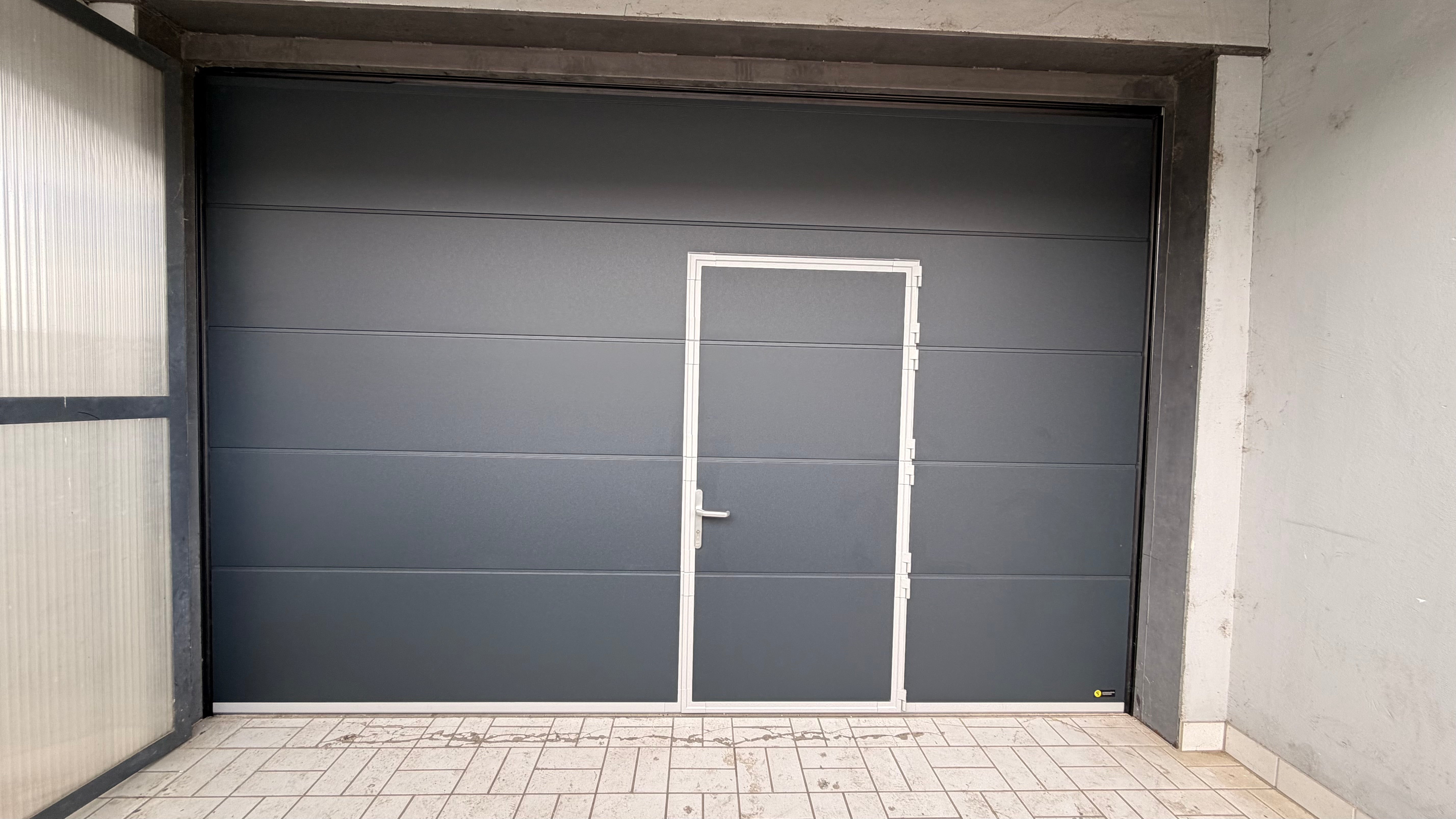 Modernes Garagen-Sektionaltor ersetzt ein altes Schwingtor, mit glatter Oberfläche, Garagentorantrieb, Handsender und Spaltabdichtung als hochwertige Modernisierung von Tormeister24.
